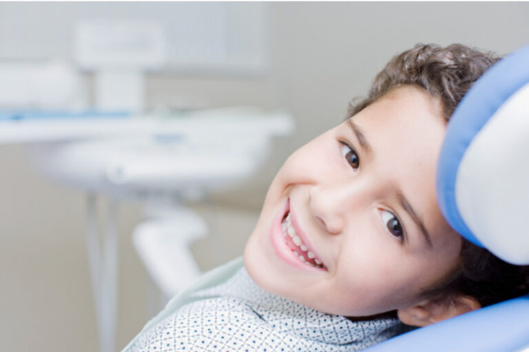 Smiling dark curly haired boy looking sideways from the dental chair