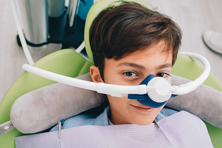 Brown haired boy in the dental chair with a nitrous oxide mask covering his nose ready for dental treatment